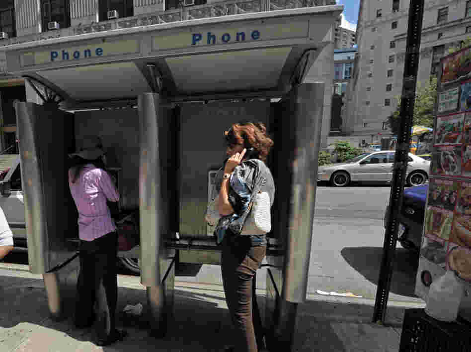 People use pay phones in Lower Manhattan. People use pay phones in Lower Manhattan.