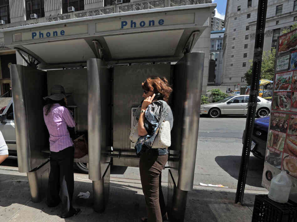 People use pay phones in Lower Manhattan. People use pay phones in Lower Manhattan.