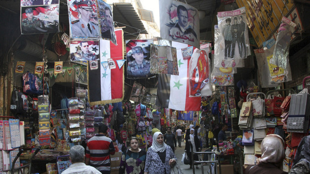 Syrians walk in the Hamidiyah market, decorated with portraits of President Bashar Assad and national flags, in the capital Damascus on Oct. 5. The European Union has intensified economic sanctions against Syria, but the crackdown against anti-regime protesters is unlikely to stop, Syrians say.
