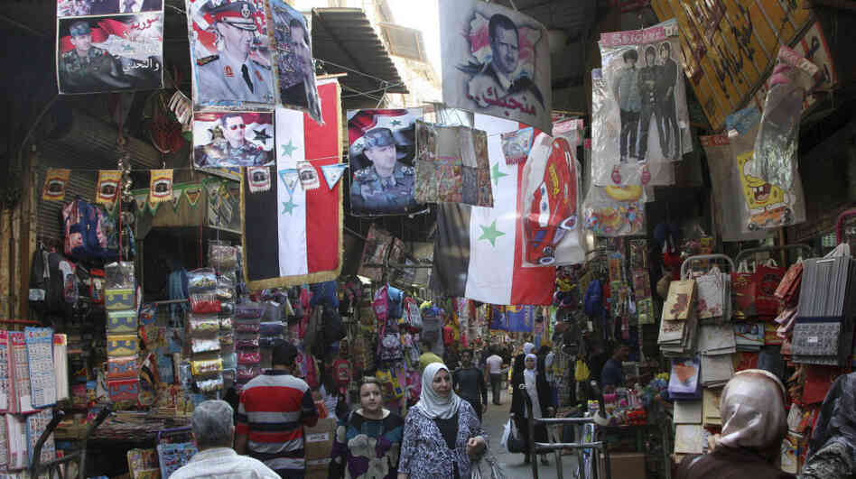 Syrians walk in the Hamidiyah market, decorated with portraits of President Bashar Assad and national flags, in the capital Damascus on Oct. 5. The European Union has intensified economic sanctions against Syria, but the crackdown against anti-regime protesters is unlikely to stop, Syrians say.