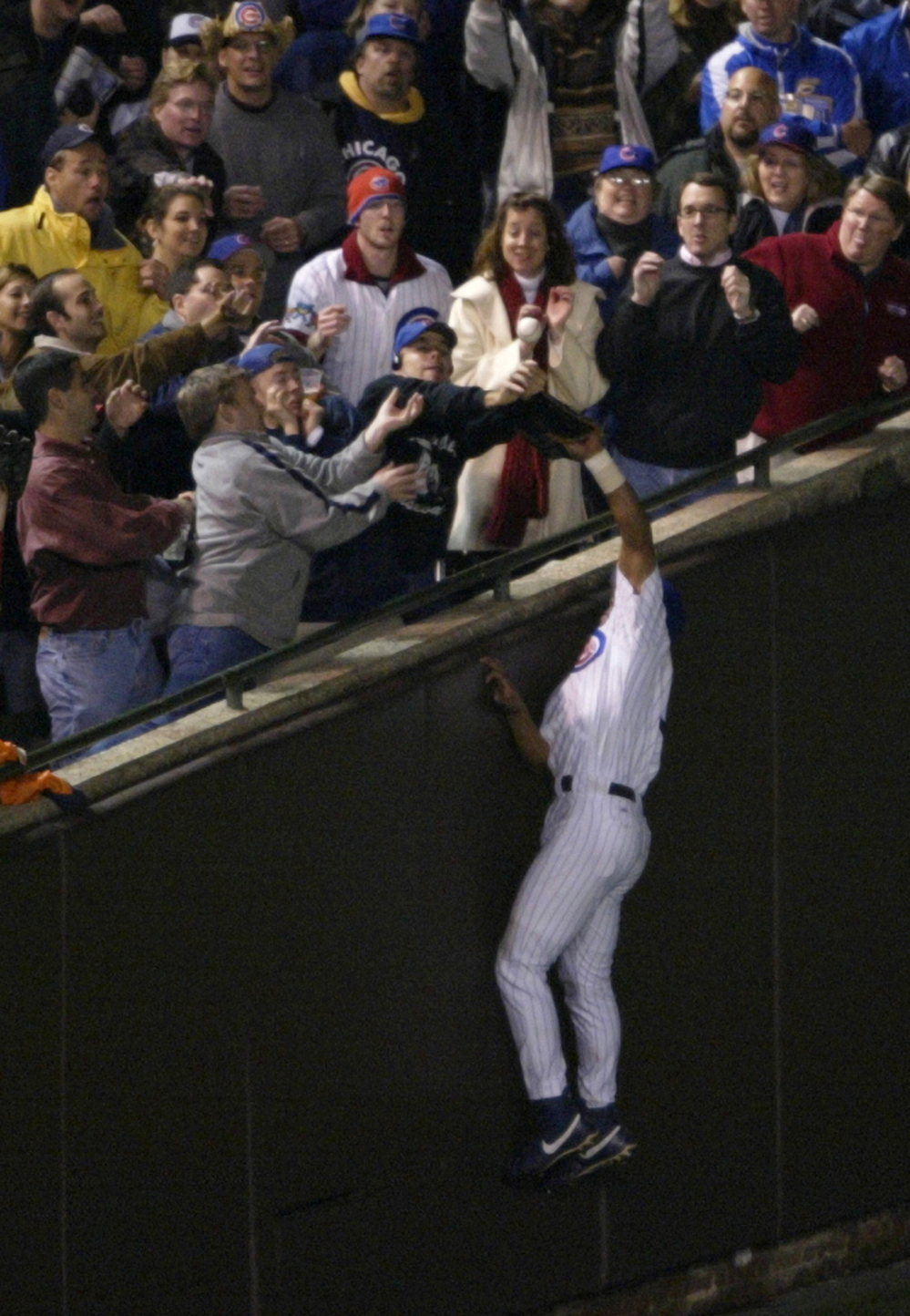As the Chicago Cubs' Moises Alou made a leaping attempt at a pop foul during the National League Championship Series, Steve Bartman (in Cubs cap and dark sweater) was among the fans reaching for the ball. While one image suggests he acted alone, the second photo tells another story.