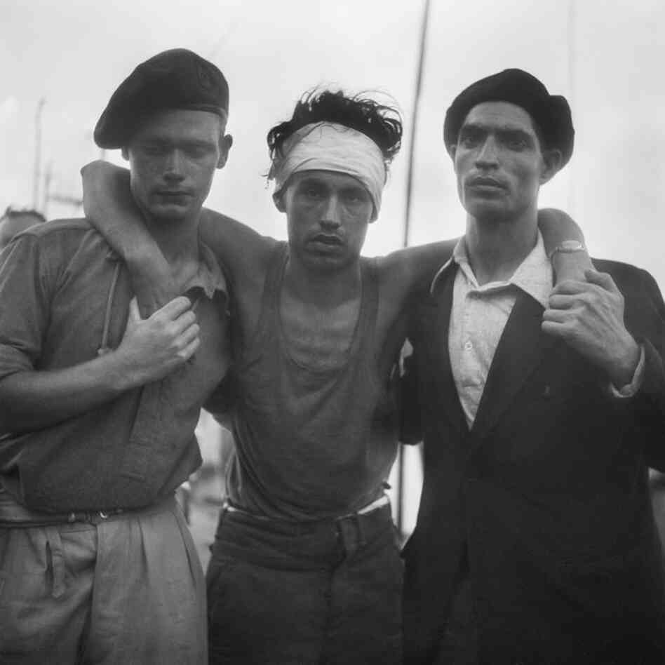 Wounded refugee aided by a British soldier and a friend, Haifa Port, July 18, 1947