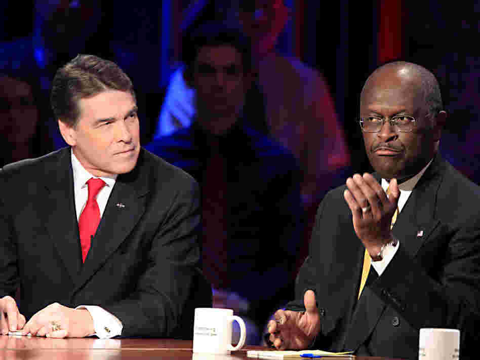 Herman Cain (right) speaks as Texas Gov. Rick Perry looks on during a GOP presidential debate at Dartmouth College on Oct. 11.