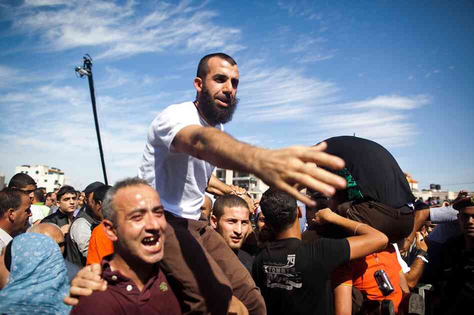 A Palestinian prisoner is held aloft in the West Bank city of Ramallah. He was one of 477 freed Tuesday, with 550 more to be freed in several months. 