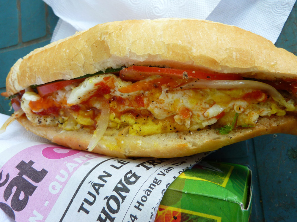 Banh mi, a ubiquitous street food in Vietnam, consists of French bread fully loaded with pate, pork, chicken, pickled carrot, daikon, cucumber and cilantro, topped with a fried egg, hot sauce and mayonnaise.