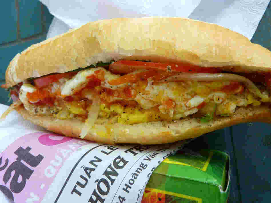 Banh mi, a ubiquitous street food in Vietnam, consists of French bread fully loaded with pate, pork, chicken, pickled carrot, daikon, cucumber and cilantro, topped with a fried egg, hot sauce and mayonnaise.