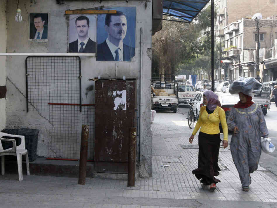Syrian women stroll past posters of President Bashar Assad in Damascus on Monday. Assad has relied heavily on his security forces as he battles an uprising now in its eighth month. 