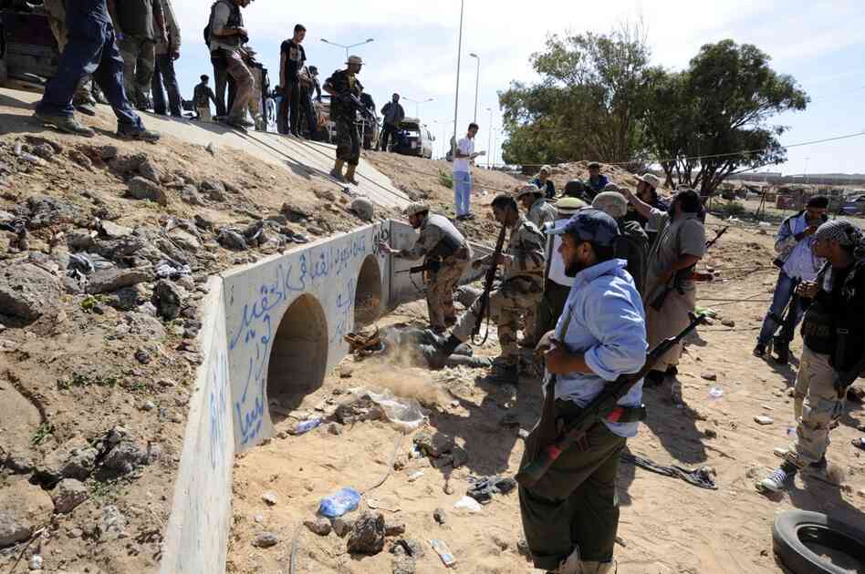 Libya NTC fighters gather outside large concrete pipes where Gadhafi was allegedly captured. 