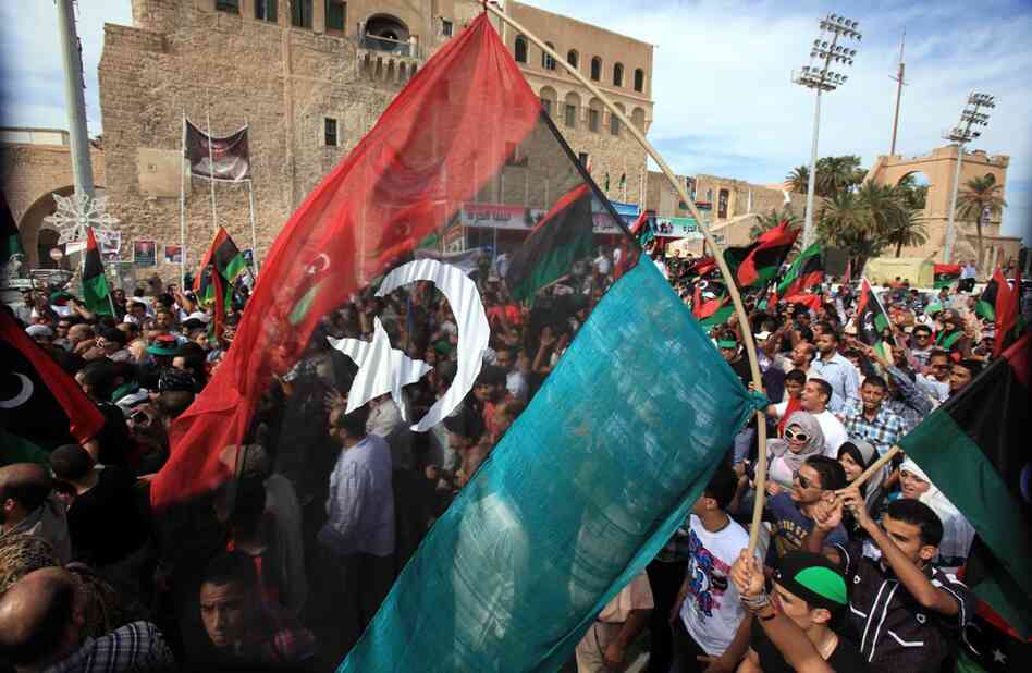 Libyans wave their new national flag as they celebrate in the streets of Tripoli. Gadhafi's capture marks the end of his 42-year rule. 