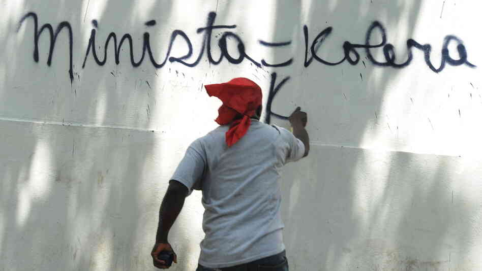 A Haitian protester in Port-au-Prince last month spray-paints a wall, equating the UN mission in Haiti (abbreviated here as MINISTA) with cholera. 