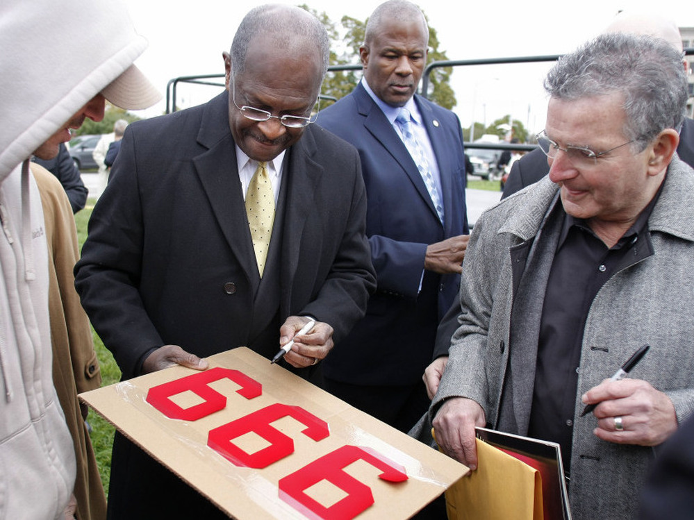On the day he revised his tax plan to 9-0-9, Republican presidential candidate Herman Cain signs a supporter's "999" sign after unveiling his "Opportunity Zone" economic plan in front of the Michigan Central Station, an abandoned train depot in Detroit.