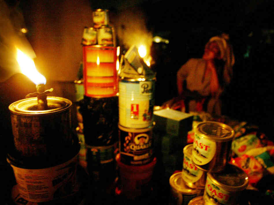 A street vendor sells her wares by the light of a kerosene wick lamp in Lagos, Nigeria. The country claims ownership of one of the world's great energy reserves, but corruption and mismanagement leave Africa's oil giant chronically short of electricity. Businesses and walled residential compounds run costly diesel generators. 