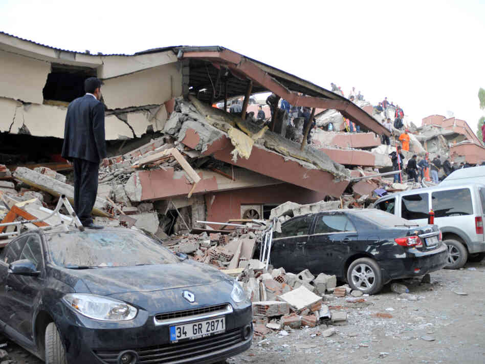 A Turkish man stands on top of a car as other Turkish men take part in a rescue operation to salvage people from a collapsed building after an earthquake in Van, in eastern Turkey on Sunday.