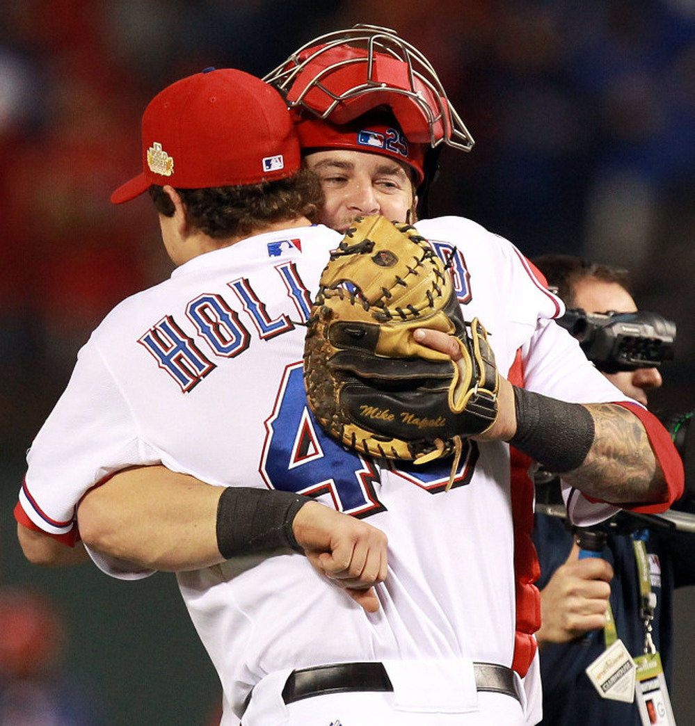 Texas Rangers pitcher Derek Holland and catcher Mike Napoli celebrate after defeating the St. Louis Cardinals 4-0 in game four of the MLB World Series.
