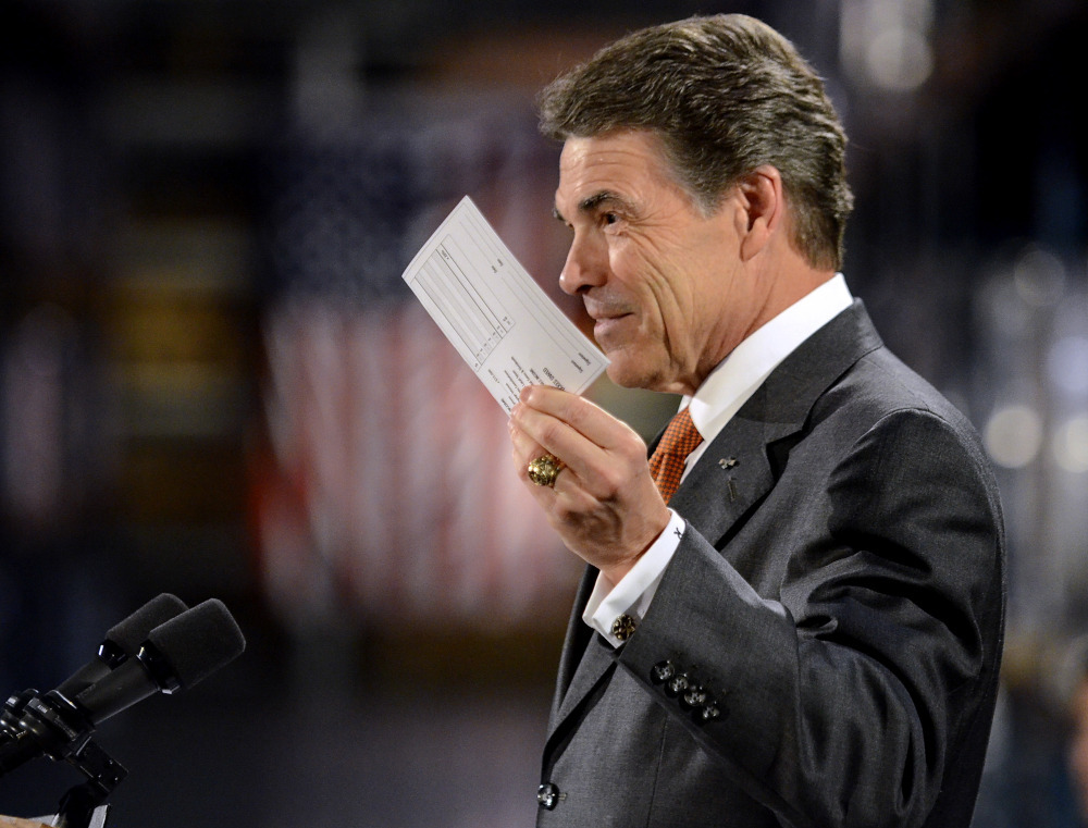 Republican presidential candidate Rick Perry holds up a postcard representing his flat tax plan Tuesday in Gray Court, S.C. Perry toured the factory and then highlighted an optional 20 percent flat tax and a deficit reduction plan. 