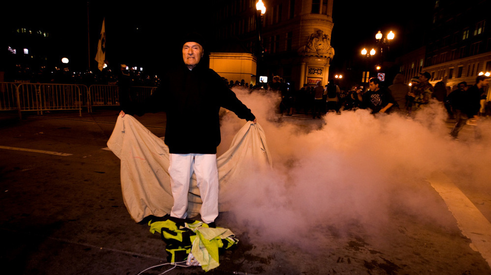 An Occupy Oakland protester stands with a banner after police used tear gas to disperse a large crowd Tuesday (Oct. 25, 2011). 