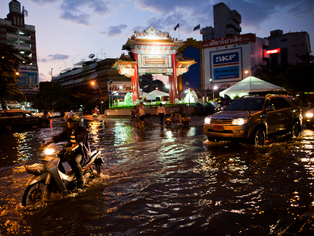 Residents drive through a flooded street close to the overflowing Chao Phraya river in Bangkok on Thursday. About 400 people have died from floods in the country since late July. 