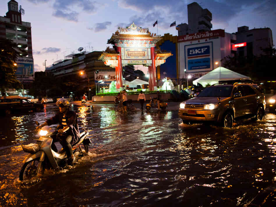 Residents drive through a flooded street close to the overflowing Chao Phraya river in Bangkok on Thursday. About 400 people have died from floods in the country since late July. 
