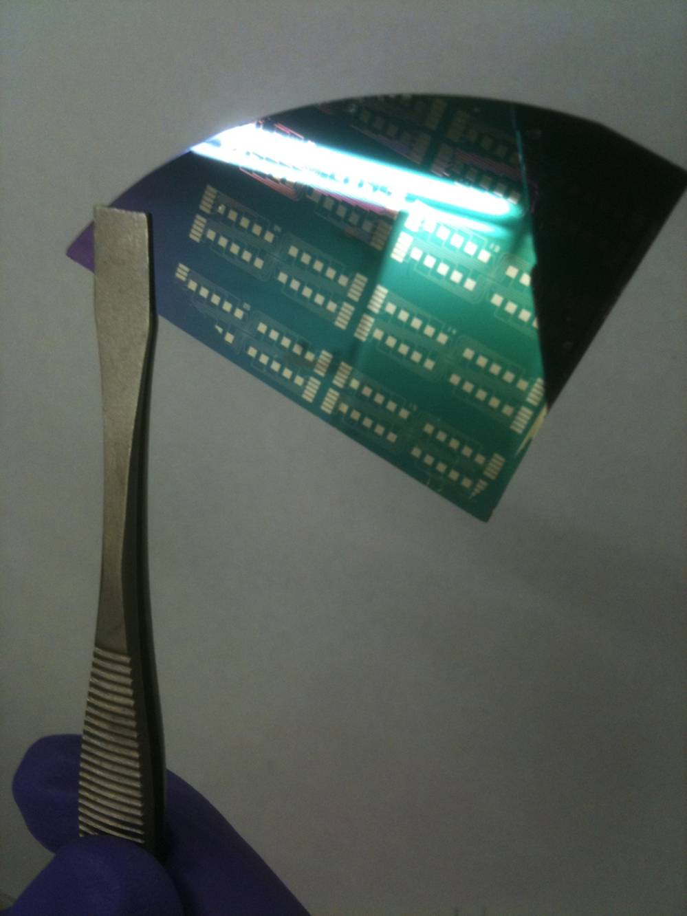 A pair of tweezers holds a graphene transistor fabricated on a silicon wafer. An I-Corps team from the University of Pennsylvania is working on scaling up their cheaper method of making high-quality graphene, an extremely strong, conductive material one atom thick that was the subject of a Nobel Prize last year.