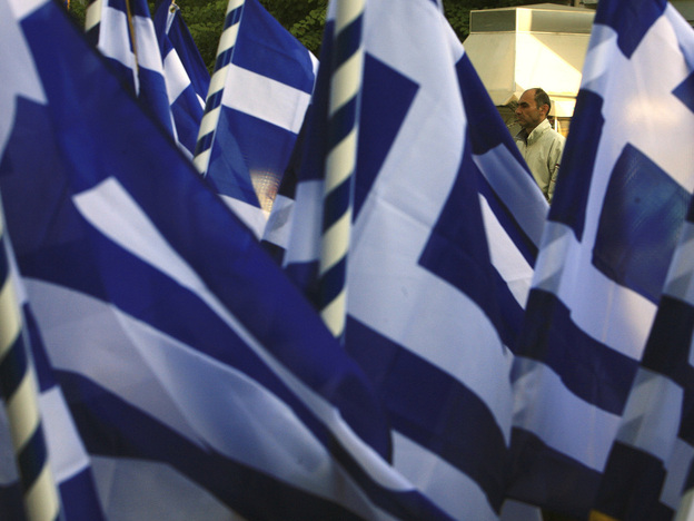 A pedestrian passes a vendor selling Greek flags in Athens on  Wednesday (Oct. 26, 2011). Greece's crushing debts triggered the latest crisis.