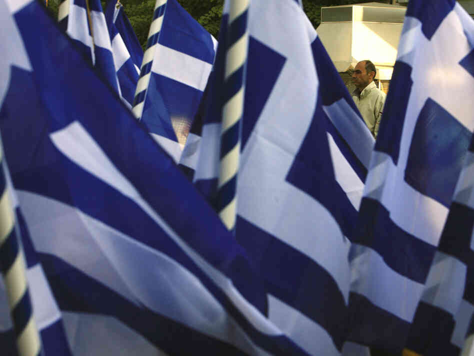 A pedestrian passes a vendor selling Greek flags in Athens on  Wednesday (Oct. 26, 2011). Greece's crushing debts triggered the latest crisis.