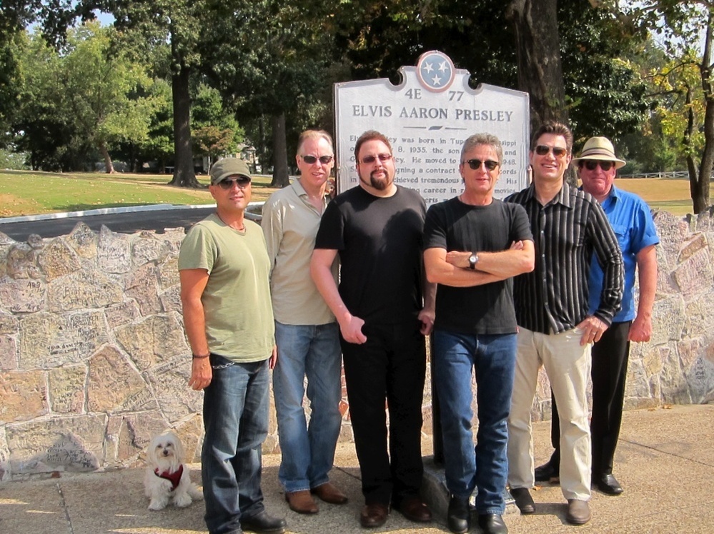 Rodney the Maltese dog takes a photo with the band at Graceland.