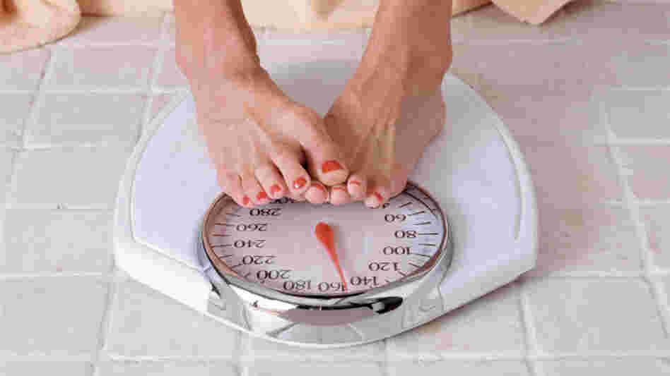 A dieter checks weight on a bathroom scale.