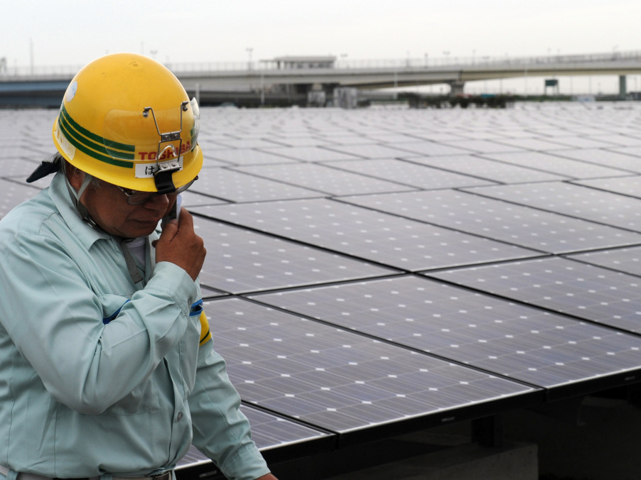 A worker stands next to an array of Sharp solar cell modules at a power plant south of Tokyo in August. Sharp was one of 1,400 solar panel manufacturers in attendance at the Solar Power International conference, where industry optimism was high.