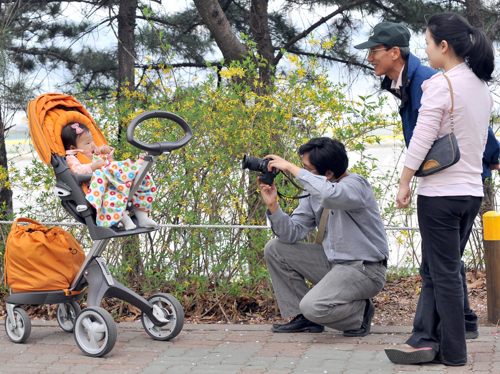 A South Korean man takes a photo of his baby during a picnic in Seoul, in 2009. After years of promoting family planning, South Korea is seeing unprecedented numbers of women staying single into their 30s — up from a handful a generation ago to 40 percent.