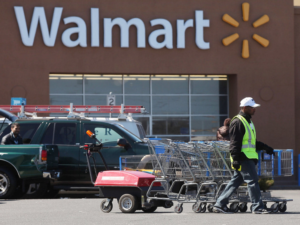 A man pushes carriages outside a Walmart store in Valley Stream, N.Y., early this year. The company is scaling back on health benefits for part-time workers.