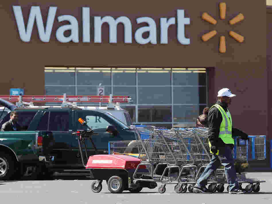 A man pushes carriages outside a Walmart store in Valley Stream, N.Y., early this year. The company is scaling back on health benefits for part-time workers.
