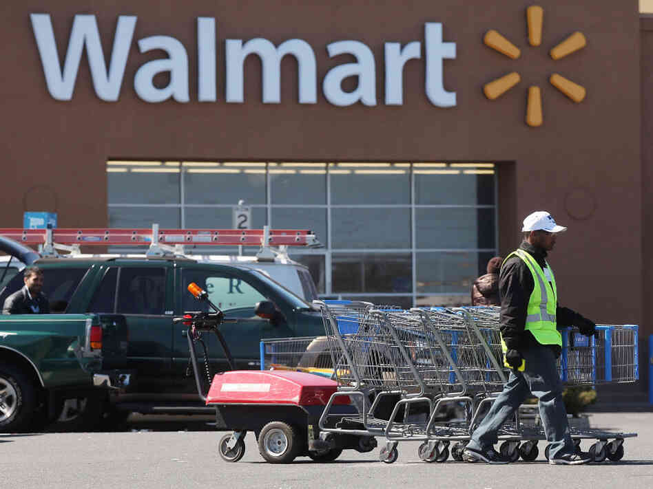 A man pushes carriages outside a Walmart store in Valley Stream, N.Y., early this year. The company is scaling back on health benefits for part-time workers.