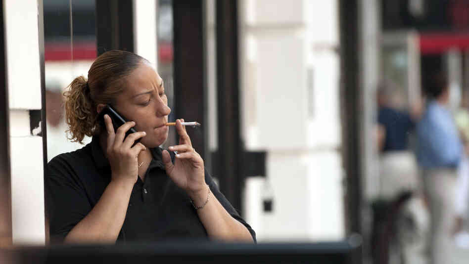 A woman smokes outside an office building in New York City. A woman smokes outside an office building in New York City.