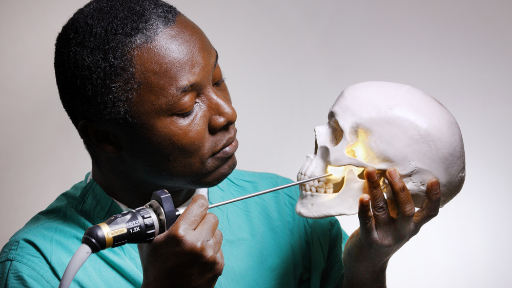 Striking a pose like Hamlet, Kofi Boahene, a surgeon at Johns Hopkins Hospital, peers through the natural opening under the cheekbone and above the jaw that he uses for surgery.