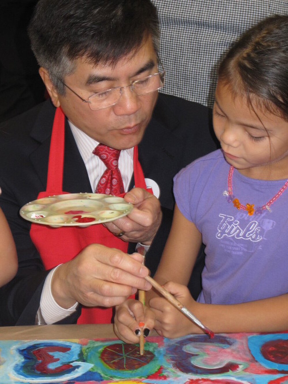Locke paints with a child during a visit to the American School of Guangzhou. He urged students to study hard, saying he regrets his inability to speak Chinese.