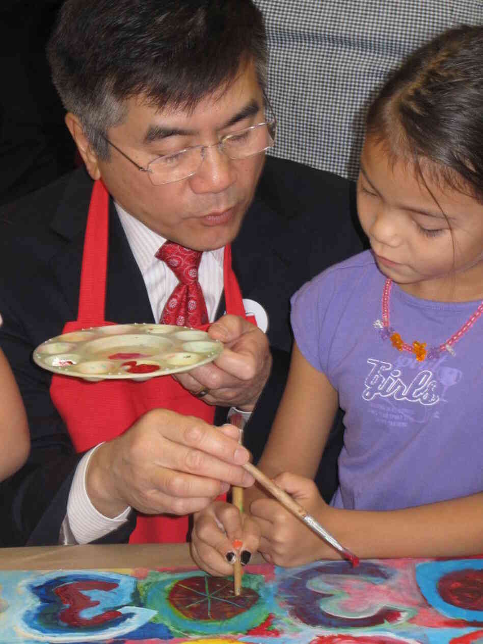 Locke paints with a child during a visit to the American School of Guangzhou. He urged students to study hard, saying he regrets his inability to speak Chinese.