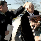 In a photo provided by the Pennsylvania Office of Attorney General, former Penn State football defensive coordinator Gerald "Jerry" Sandusky, center, is placed in a police car iin Bellefonte, Pa., to be taken to the office of a Centre County Magisterial District judge on Saturday, Nov. 5, 2011.