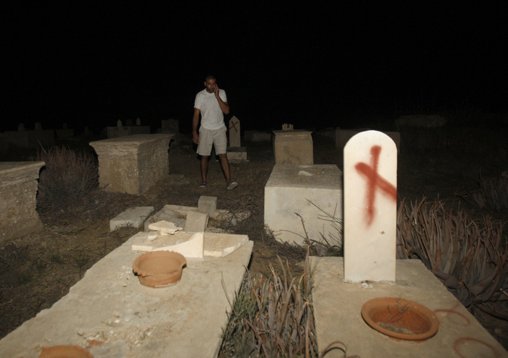  A man stands near tombstones vandalized in a cemetery in Jaffa, Israel, on Oct. 8. Headstones at the Muslim and Christian cemetery were defaced with messages like "Death to Arabs." 