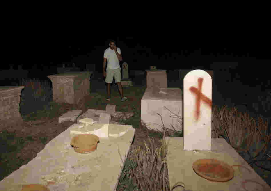  A man stands near tombstones vandalized in a cemetery in Jaffa, Israel, on Oct. 8. Headstones at the Muslim and Christian cemetery were defaced with messages like "Death to Arabs." 