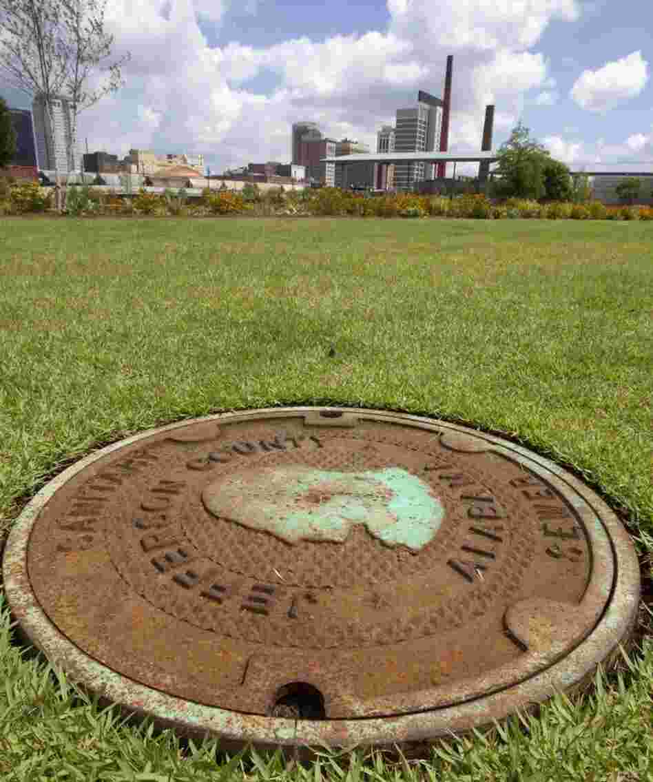 This file photo shows a Jefferson County sewer manhole cover in Railroad Park in Birmingham, Ala. Leaders of Alabama's most populous county voted to file an estimated $4.1 billion bankruptcy.