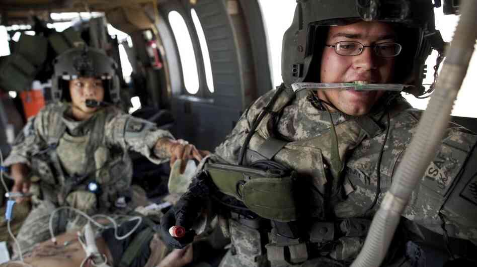 Army flight medics work on a Marine who was wounded by an improvised explosive device, or IED, in southern Afghanistan.
