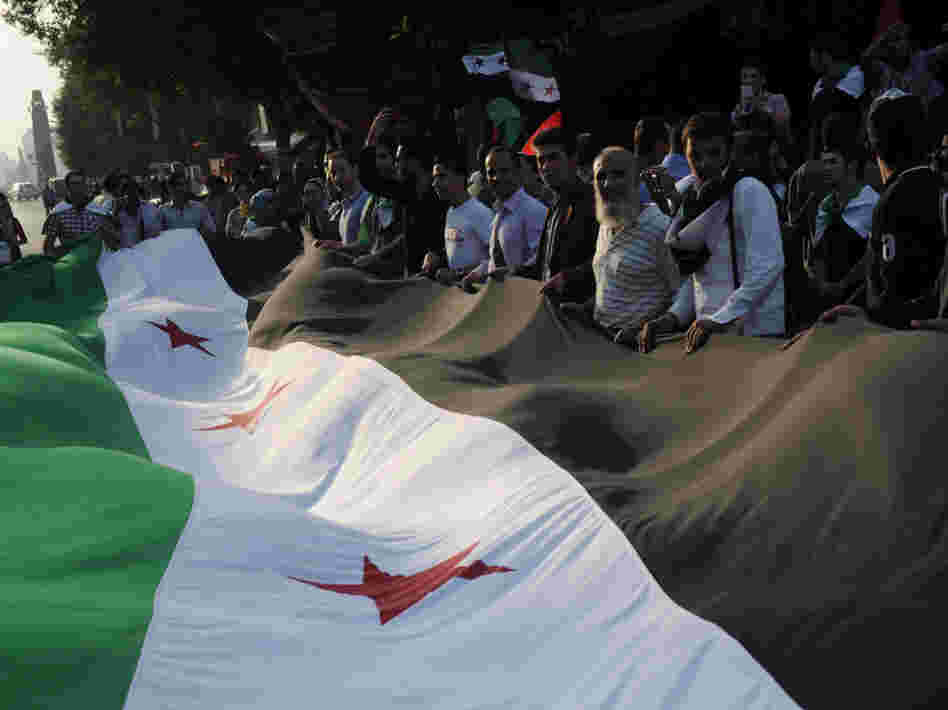 Pro-democracy protesters, holding a huge pre-Baath era Syrian flag outside the Arab league headquarters in Cairo on November 2, 2011.