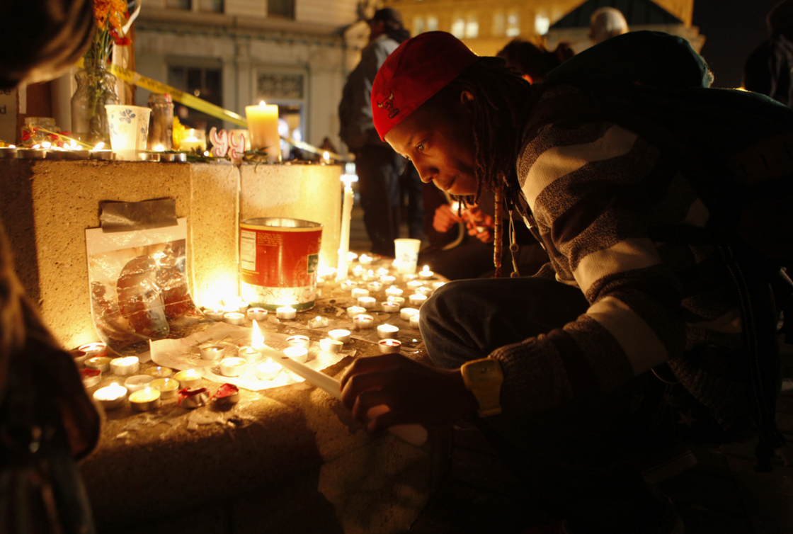 An Occupy Oakland demonstrator lights a candle after a man was shot and killed near the Occupy Oakland camp.
