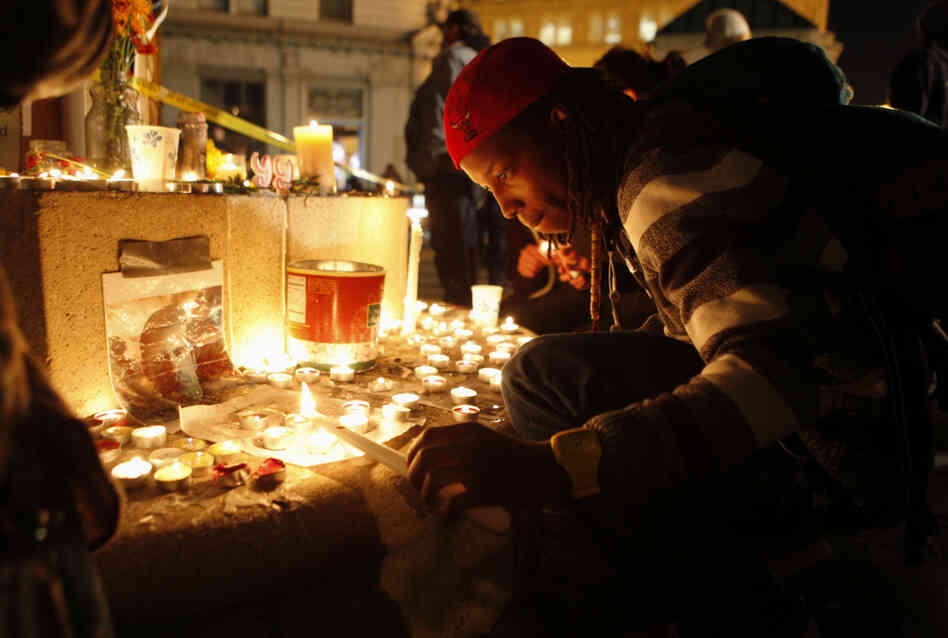 An Occupy Oakland demonstrator lights a candle after a man was shot and killed near the Occupy Oakland camp.