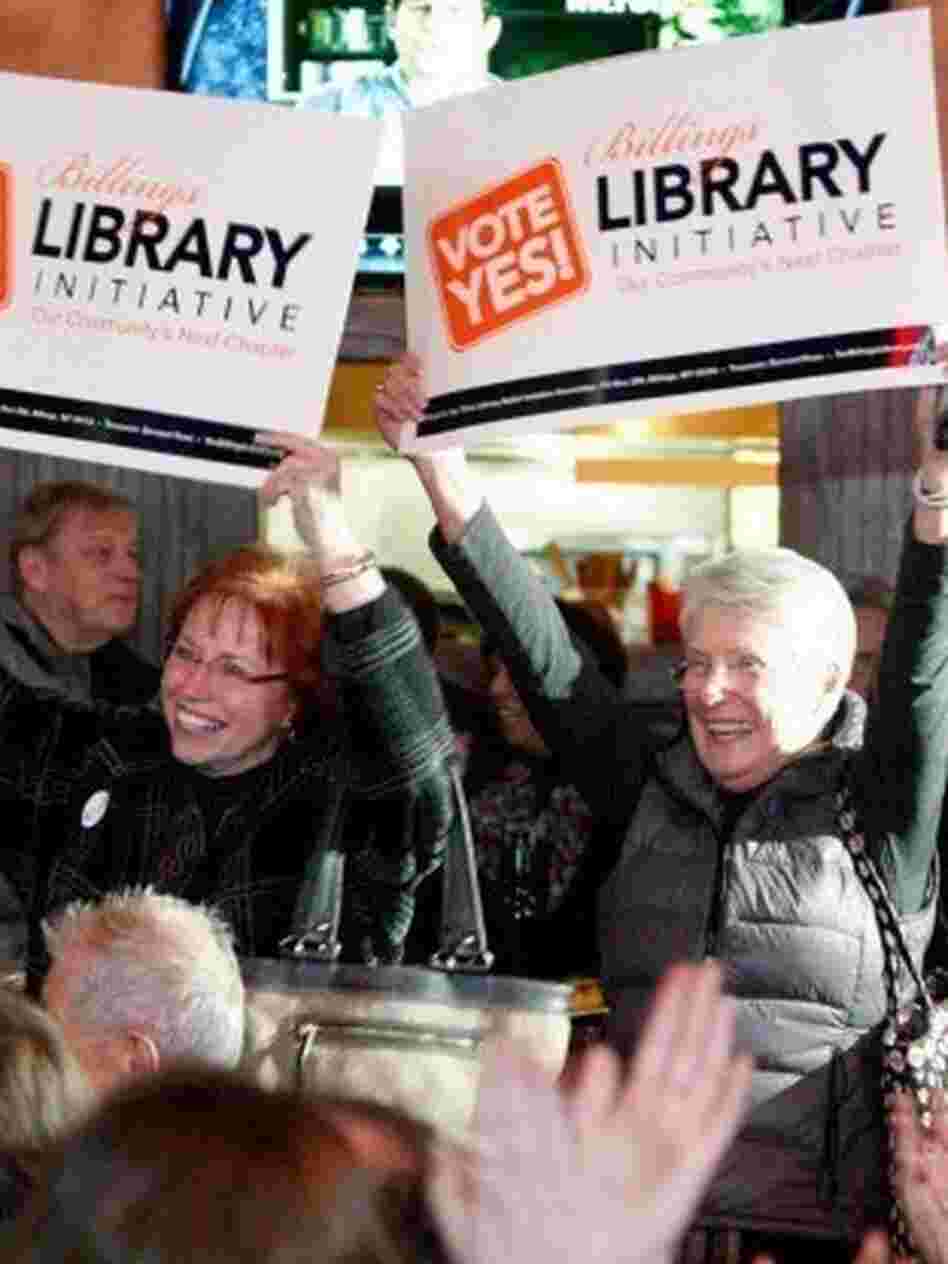 Billings Library Foundation Board President Evelyn Noennig (left) and Suzanne McKiernan arrive at a bar carrying signs to support an initiative for a library bond, as patrons gathered to watch election results. 