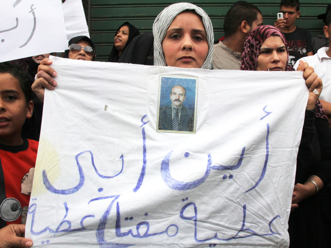A woman outside the Hudba el-Gassi compound in Tripoli, Libya, holds up a sign asking, "Where's my father?" Once a military police base, Hudba el-Gassi is now a makeshift prison for regime loyalists and others rounded up by armed militiamen. 