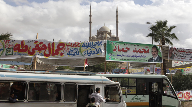 Election banners hang near buses in Cairo on Monday. Parliamentary elections — the first since the end of President Hosni Mubarak's decades-long rule — will begin Nov. 28. Groups with Islamist ties are expected do well in the polls.