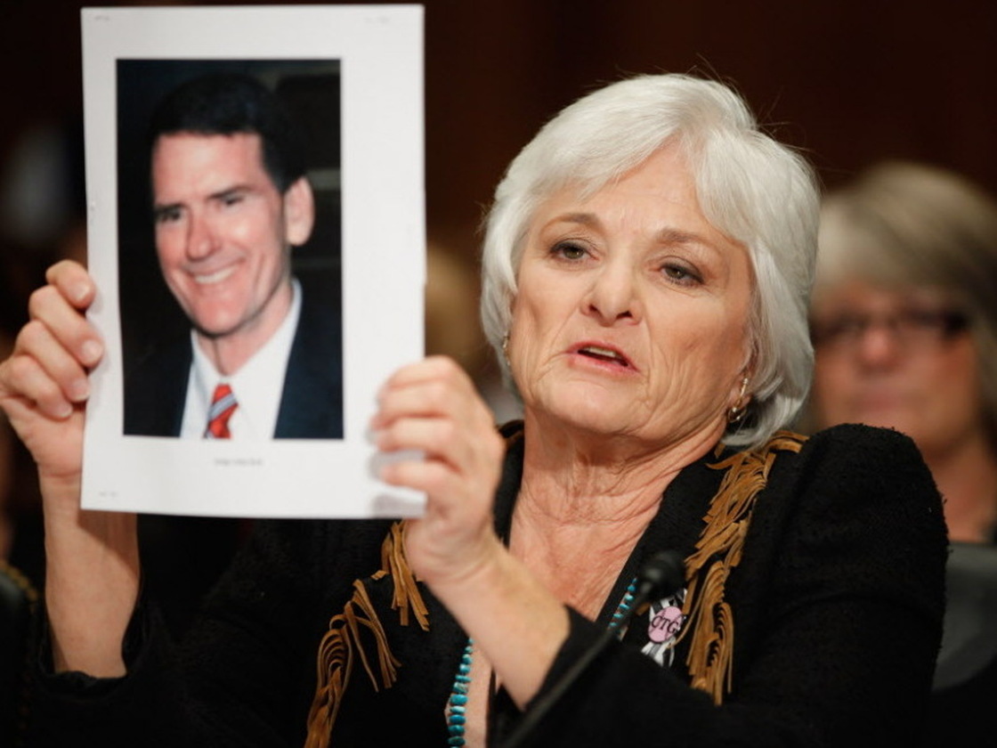 Patricia Maisch, one of the people who helped halt the Tucson shooting that killed six and wounded 13, including Arizona Rep. Gabrielle Giffords, holds up a photograph of victim John Roll, a federal judge, while testifying before a Senate subcommittee on Tuesday. Maisch testified in support of legislation that would strengthen federal power over the states' handling of background checks.