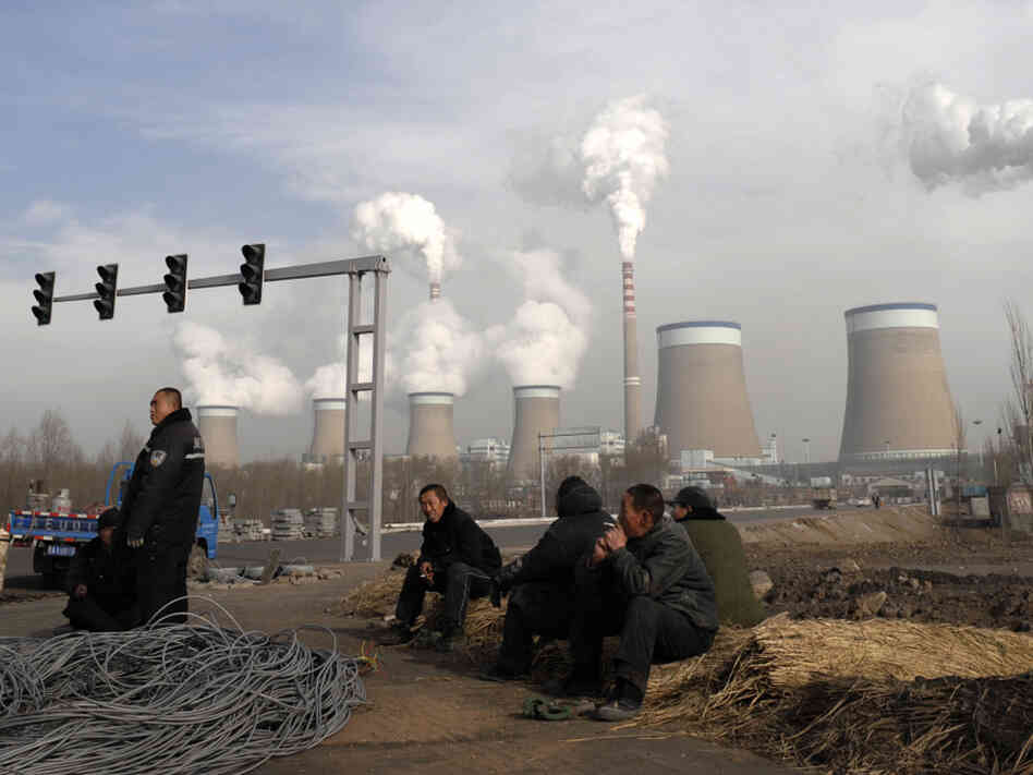 Workers take a break in front of the cooling towers of a coal-fired power plant in Dadong, Shanxi province, China. At a House hearing on Tuesday, Nisha Biswal defended USAID's programs in China, saying the money goes to efforts that include reducing harmful emissions from the country's power plants.