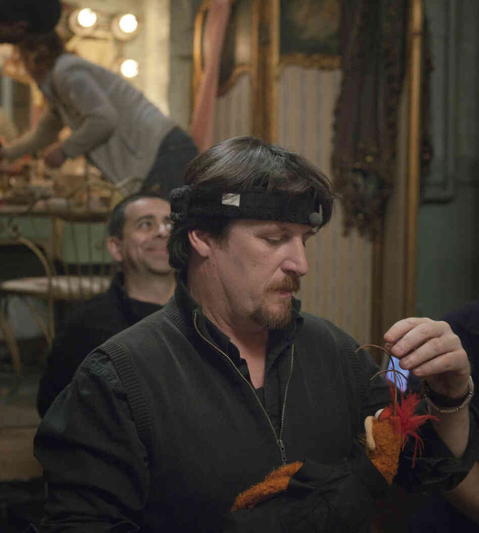 Muppet wrangler Bill Barretta — wired for sound with a headband microphone — adjusts one of Pepe the Prawn's antennae.